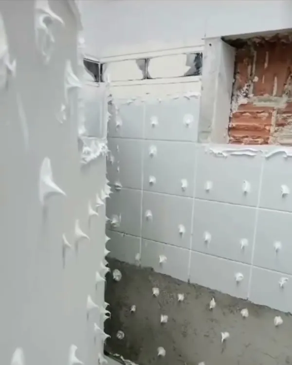 Instalação do revestimento no banheiro durante a execução.